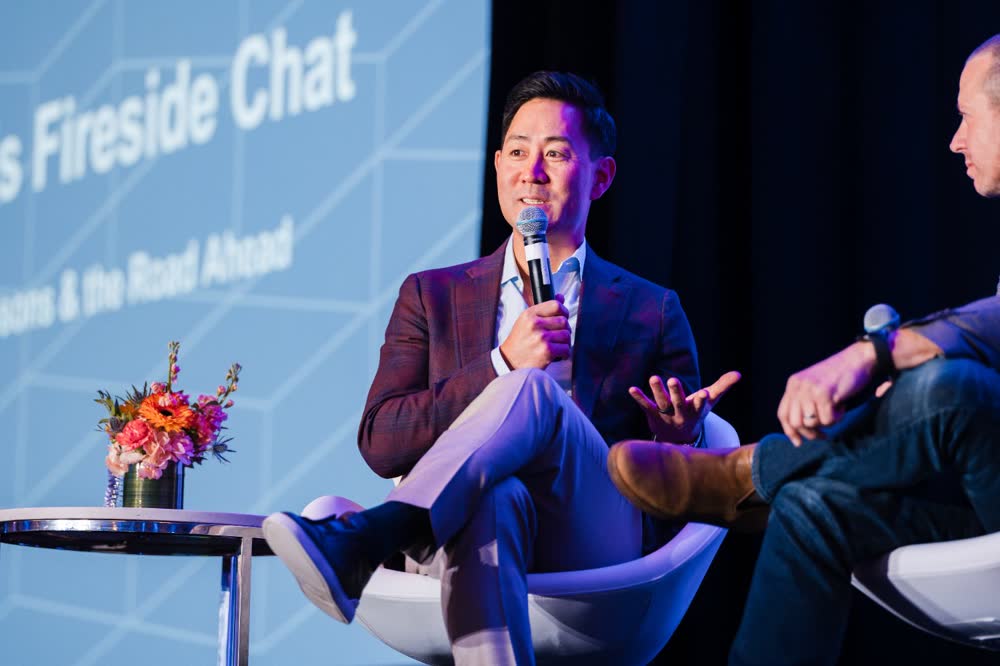 A panelist speaks into a handheld microphone at a corporate event