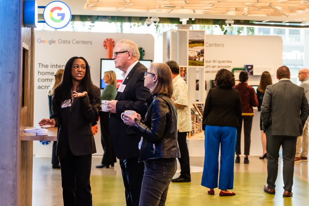 A presenter demonstrates a wall display to guests at a corporate event