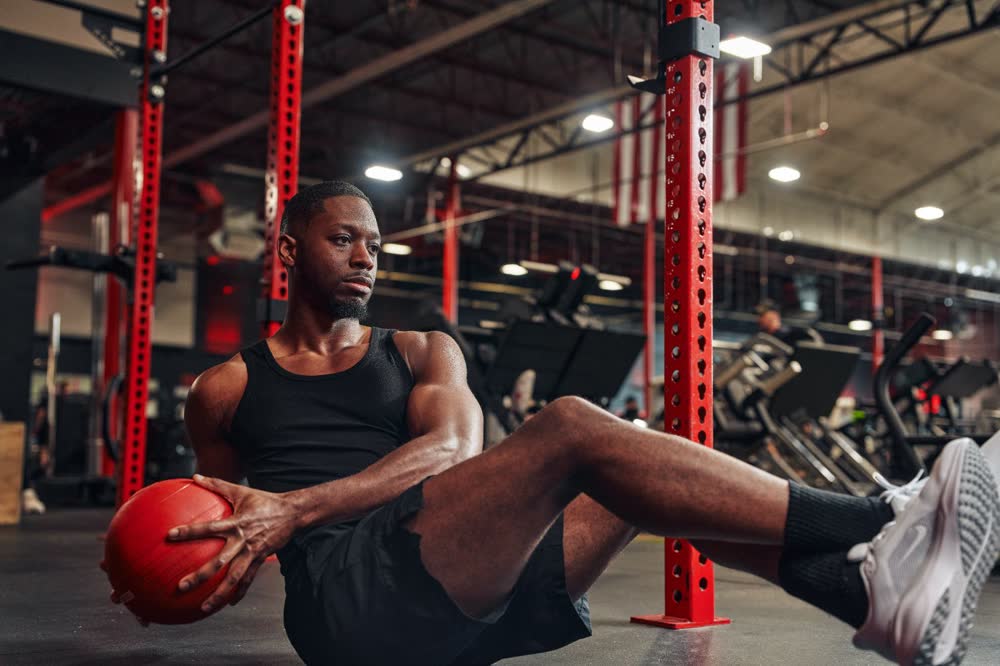 Athlete performing a seated medicine ball twist on a gym floor