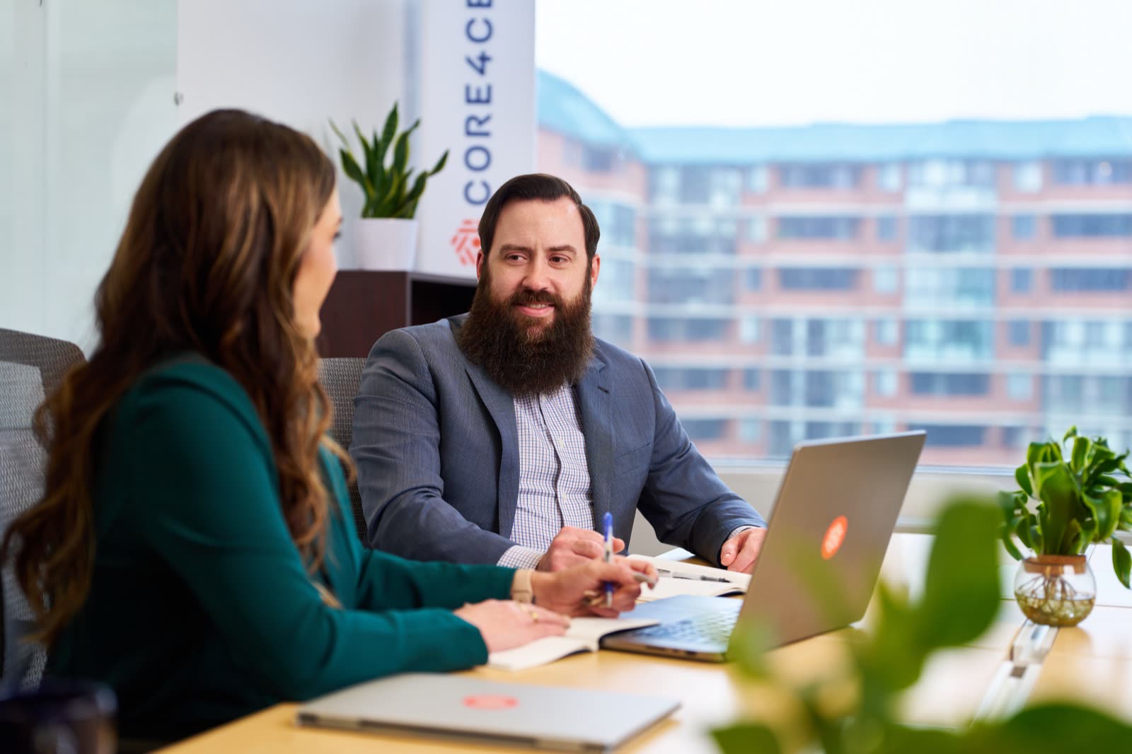 Colleagues collaborate around a laptop in a bright conference room.